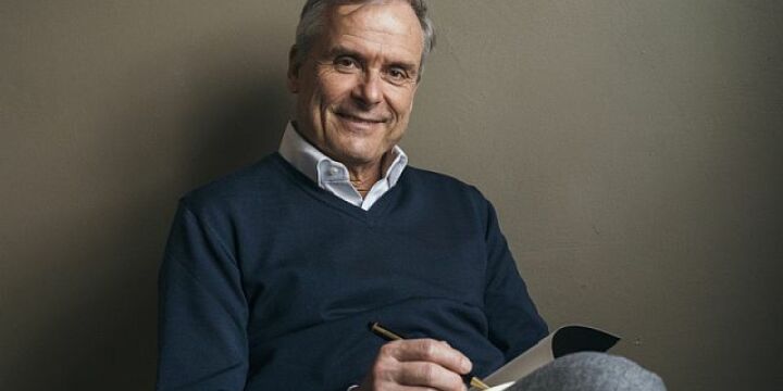 Axel Hacke sitzt und liest ein Buch